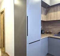 The kitchen of a three-room apartment with a wooden decor floor and modern equipment.