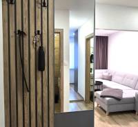 Hallway with a mirror, coat rack, and a view into the living room. Floor with a wooden decor.