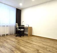 A workspace with a desk in a 3-room apartment with a wooden decor floor.