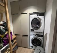 Laundry room with lockers, washing machine, and dryer in a 4-room apartment. Floor with wood decor.