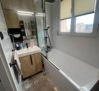 Bathroom in a 4-room apartment with a bathtub, sink, mirror, and colorful tiles.