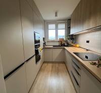 A kitchen in a 4-room apartment with a wooden decor floor, light cabinets, window.