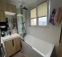 A bathroom with a shower and a bathtub in a 4-room apartment with a wooden decor.