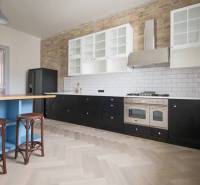 A stylish kitchen with a wood-patterned floor in a 4-room apartment, with a brick wall cladding.