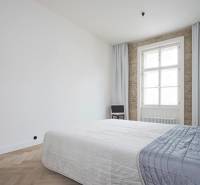 A bedroom with a blue bed, light curtains, and a wooden decor floor in a 4-room apartment.