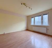 An unfurnished room with wood-patterned flooring and a large window in a 4-room apartment.