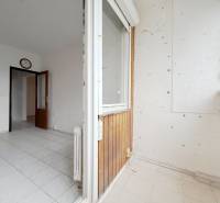 A balcony with tiles in a 4-room apartment, view into the hallway with doors.