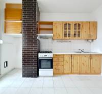 A kitchen with wooden cabinets, a stove, and a white floor in a 4-room apartment.