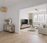 A bright living room with a sofa set, wood-patterned flooring, and a television in a four-room apartment.