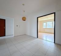 A tiled hallway leads to a bright living room with access to a floor with a wooden decor.