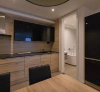 A kitchen in a 2-room apartment with a wood-patterned floor and an installed television.