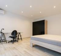 A bedroom in a two-room apartment with simple furniture and a wooden decor floor.