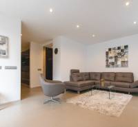Living room in a two-room apartment with a sofa, armchair, carpet, and paintings on the wall.