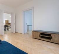 Living room of a three-room apartment with a blue sofa and a wooden decor floor.