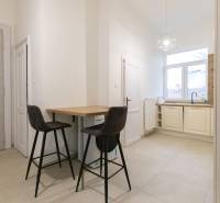 A kitchen in a 3-room apartment with a bar counter, two chairs, and a large window.
