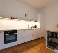 Kitchen in a 2-room apartment with white cabinets and a wooden decor floor.