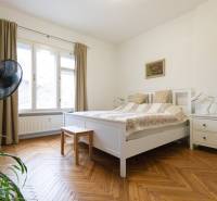 A bedroom with light furniture, a large window, and a floor with a wood decor in a 2-room apartment.