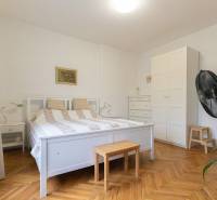 A bedroom in a 2-room apartment with white furniture and a wooden decor floor.