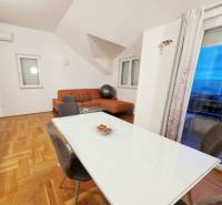 Dining room and living room in a holiday apartment with wood-patterned flooring.