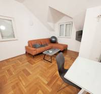 Recreational apartment with an orange sofa and a wooden decor floor.