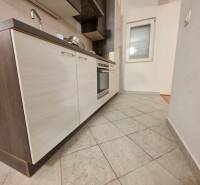 A kitchen in a holiday apartment with tiled flooring and a modern unit with dark cabinets.