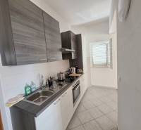 The kitchen of a holiday apartment with modern equipment and a window that illuminates the space.