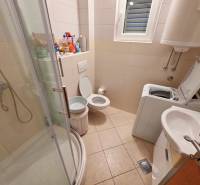 Bathroom in a Holiday Apartment with a toilet, shower, and washing machine.