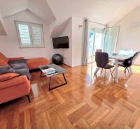 Recreational apartment with an orange sofa, dining table, and wood-patterned flooring.