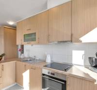 Kitchen area in a 3-room apartment with light wooden cabinets and appliances.