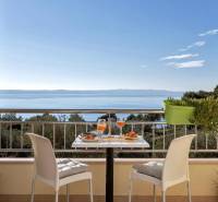The balcony of a 3-room apartment in Makarska with a sea view and a table with drinks.