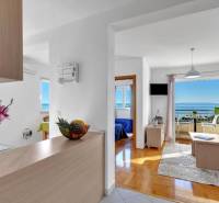 A bright living room with wood-patterned flooring and a sea view in a 3-room apartment.