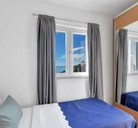 A bedroom in a 3-room apartment with a view of the sea through the window.