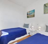 Bedroom in a 3-room apartment with two beds, white furniture, and a wooden decor floor.