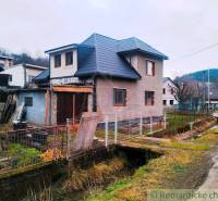 A family house in Jasenica with a sloped roof, fence, and adjacent road.