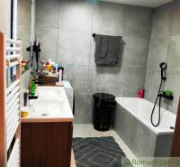 Bathroom with a bathtub, double sink, mirror, and bathroom radiator in a family house.