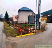 A family house in Jasenica by the road with a drainage channel and a fence.