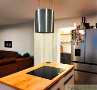 A kitchen in a family house with a cooktop, a sofa, and a stainless steel refrigerator.