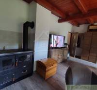 Living room in a family house with a stove, television, and wooden ceiling.