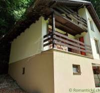A family house in Mojtín with a wooden balcony surrounded by greenery and trees.