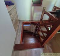 A staircase with a wooden railing in a family house, next to it are drawer cabinets.