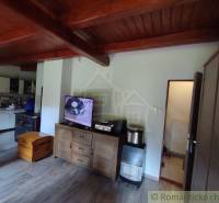 Interior of a family house with a wooden decor floor, television, and kitchen unit.