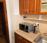 A kitchen unit with a sink, microwave, and kettle in a 3-room apartment.