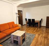 3-room apartment with an orange sofa, wooden table, and wooden decor flooring.