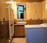 A bathroom in a 3-room apartment with light tiles, a sink, and a washing machine.