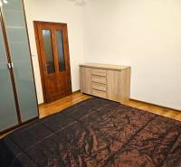 Bedroom in a 3-room apartment with a wooden decor floor, wardrobe, and dresser.