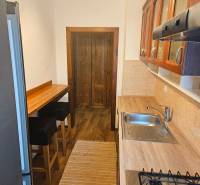A kitchen in a 3-room apartment with a wood-patterned floor, a bar counter, and appliances.