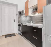A kitchen in a 2-room apartment with black cabinets and gray tiles.