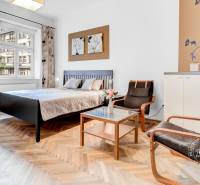 Bedroom in a 2-room apartment with a bed, chairs, and a wooden decor floor.
