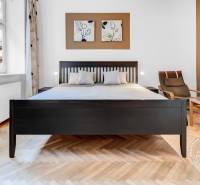 A bright room with a bed, a chair, and a wooden decor floor in a two-room apartment.