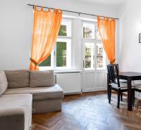 Living room in a two-room apartment with a sofa, table, and orange curtains.